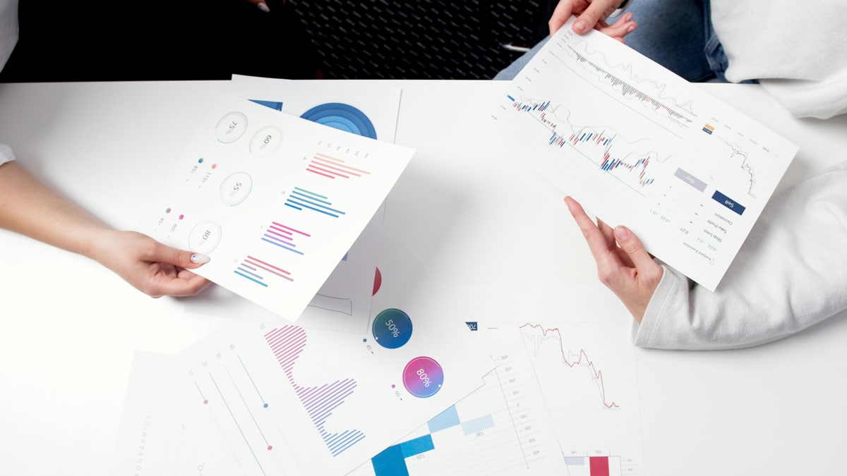 Person-holding-charts-and-data-tables-over-a-table
